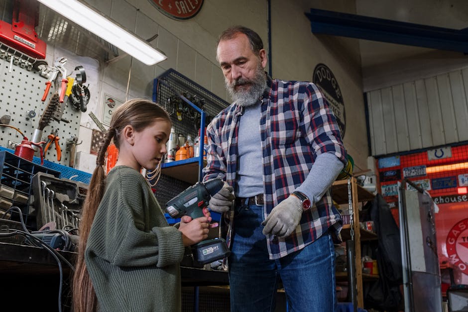 Father and daughter share bonding time in an auto workshop, using power tools.